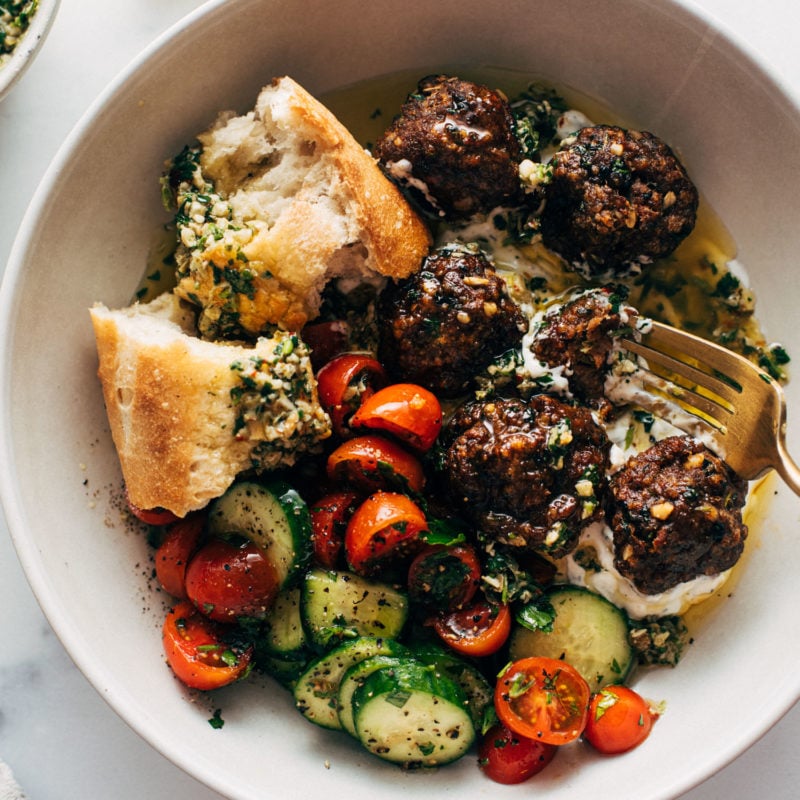 Meatballs in a bowl with a tomato salad, fork, and bread
